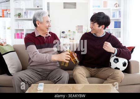 Sorridente padre anziano e suo figlio giovane con un brindisi di calcio Foto Stock
