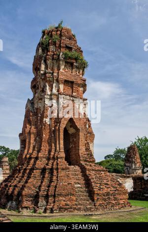 Alto prang di mattoni intemprati che si innalza drammaticamente contro un cielo blu al Parco storico di Ayutthaya, Thailandia, mostrando dettagliate antiche murature. Foto Stock