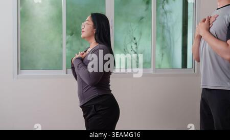 Donna e uomo asiatici che praticano meditazione sulla consapevolezza a casa Foto Stock