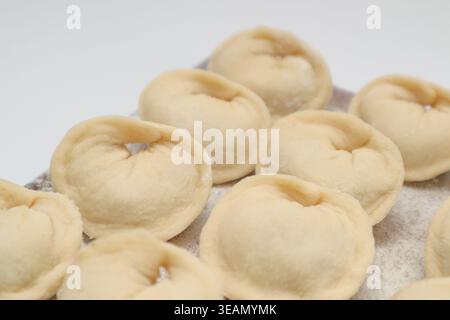 Preparazione di gnocchi Pelmeni. Pelmeni a base di carne cruda, ravioli, gnocchi vista dall'alto su una tavola di legno Foto Stock
