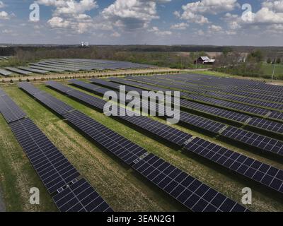 Vista aerea di un vasto array di pannelli solari che si estende attraverso il paesaggio, in contrasto con alberi ed edifici lontani, Lebanon, Ohio, Stati Uniti. Foto Stock