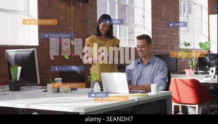 Modello con camicia blu e top di senape che si abbina a un laptop argentato con rivestimento social. Openplan, collaborazione, coworking, Brick, Windows, Foto Stock