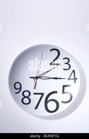 Un orologio a parete visualizza l'ora alle 15:45 in un design moderno, bianco e semplice. Foto Stock