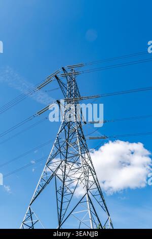 Vista verso l'alto di un alto pilone che trasporta cavi elettrici ad alta tensione Foto Stock