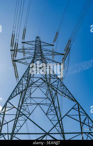 Vista verso l'alto di un alto pilone che trasporta cavi elettrici ad alta tensione Foto Stock