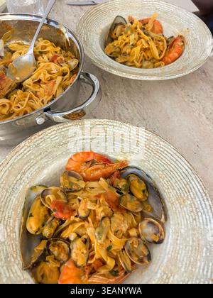 Una deliziosa pasta a base di pesce con gamberi, cozze e fettuccine, servita in una salsa cremosa per un pasto saporito e appagante. Foto Stock