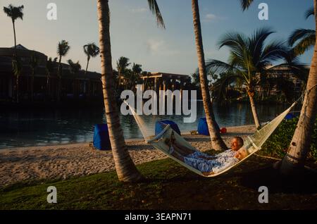 Una coppia più anziana si rilassa in un'amaca doppia in un hotel esclusivo sull'isola di Maui, Hawaii. Foto Stock