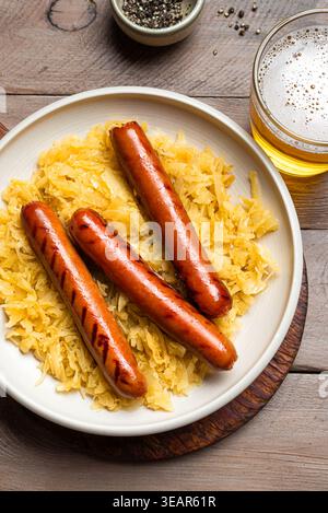 Abbondante pasto tedesco: Bratwurst con crauti e tazza di birra da vicino. Tradizionale cucina bavarese dell'Oktoberfest, Kraut e salsicce. Foto Stock