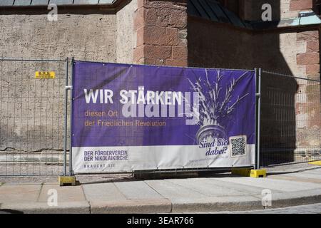 Lipsia, Germania - 22 aprile 2026: Banner viola per la raccolta fondi per la chiesa di San Nicola su una recinzione di costruzione, che menziona la rivoluzione del 1989. Foto Stock