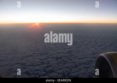 Vista dalla finestra di un aeroplano che si affaccia su uno splendido tramonto viola e arancione. Foto Stock
