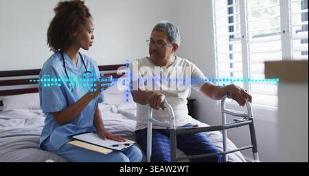 Infermiera parlante in scrub blu con appunti, consigliando al paziente di usare un deambulatore in camera da letto, mascherina blu Foto Stock