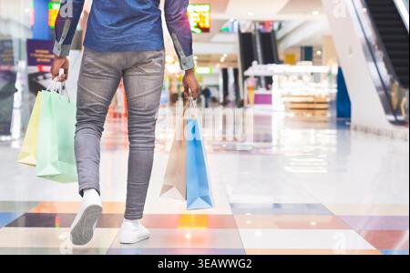 Uomo africano irriconoscibile con borse per lo shopping nel centro commerciale Foto Stock