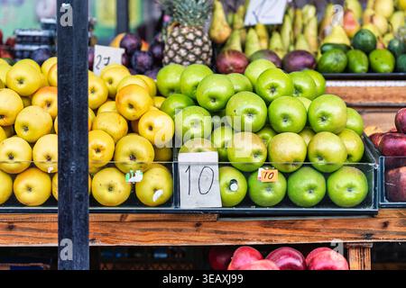 Mercato della frutta di Batumi con mele verdi e gialle fresche e frutta assortita, come ananas e prugne, sotto la luce naturale Foto Stock