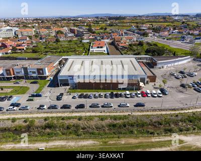 Vista aerea di un grande edificio con tetto ondulato circondato da auto parcheggiate ordinatamente, Águeda, Portogallo. Foto Stock