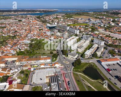 Vista aerea dei tetti in terracotta in contrasto con gli edifici moderni, tagliati in due da strade tortuose vicino all'acqua, Aveiro, Portogallo. Foto Stock
