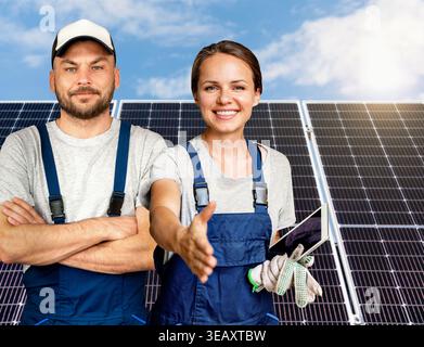 Diversi team di installatori di pannelli solari professionali che offrono una stretta di mano davanti ai pannelli solari. Concetto di partnership per l'energia verde. Foto Stock