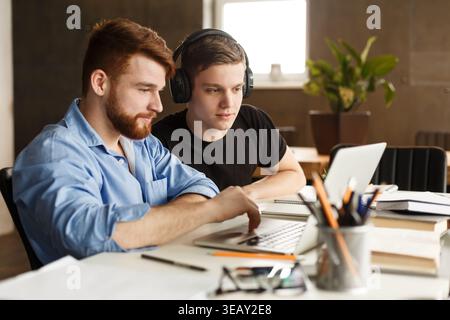 Due giovani che collaborano a un progetto in un Bright Indoor Workspace durante il giorno Foto Stock