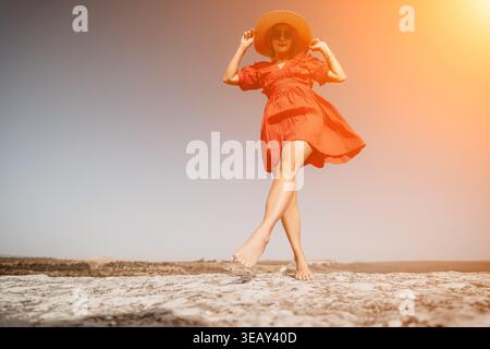 Donna in abito rosso che cammina su una scogliera Foto Stock
