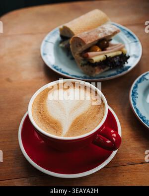 primo piano di un caffe' latte con un sandwich a lievitazione naturale su un tavolo da caffe' Foto Stock