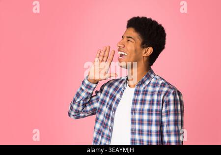 Attenzione. Giovane ragazzo in camicia a scacchi che tiene la mano vicino alla bocca Foto Stock