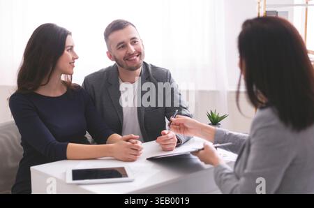 Giovane coppia che discute i piani con il consulente finanziario in un ambiente moderno Foto Stock