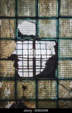 Vecchio muro di vetro rotto, focalizzazione selettiva. All'interno dell'edificio industriale, fabbrica abbandonata Foto Stock
