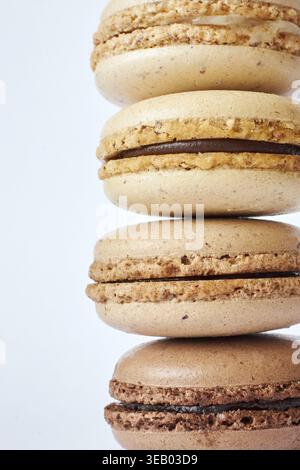 Pila di quattro macaron francesi marroni, torte dai gusti diversi, caffè e creme brulee. Piramide di dessert fatti in casa, macaron vista laterale, C Foto Stock