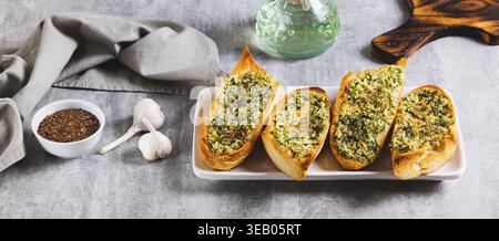 Baguette al forno con burro, aglio e aneto su un piatto sul banner del tavolo Foto Stock