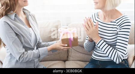 Giovane donna che si congratula con la madre anziana con la confezione regalo Foto Stock