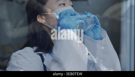 Regolazione del medico coreano posizionamento di occhiali sulla maschera in vetro con un rivestimento bianco con stetoscopio e guanti Foto Stock