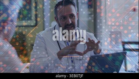 Medico parlante che indossa un cappotto bianco e uno stetoscopio appoggiato in clinica, con laptop, grafica del circuito Foto Stock