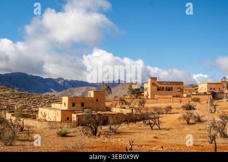 Arido paesaggio dai toni caldi e piccole case antiche situate sulle montagne dell'Atlante, nel distretto di Agadir, in Nord Africa. Foto Stock
