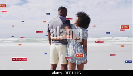 Coppia che si affaccia sull'oceano in spiaggia, uomo in tee, donna in abito blu, con sovrapposizioni grafiche Foto Stock