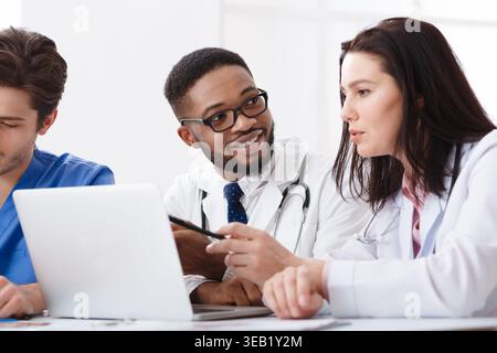 Due medici consulenza, utilizzando laptop in ufficio Foto Stock