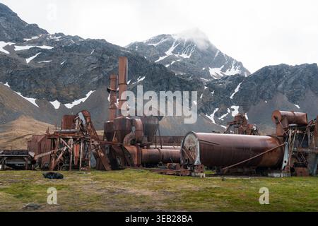 Vista dei macchinari industriali arrugginiti presso la storica stazione baleniera di Grytviken con montagne innevate sullo sfondo Grytviken, Georgia del Sud Foto Stock