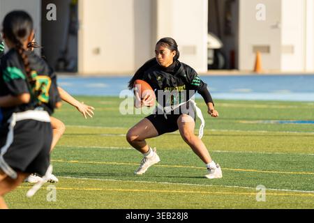 Flag Football - atleta femminile che corre la palla come difensore chiude durante la partita Kaiser vs Kaimuki Junior Varsity High School Foto Stock