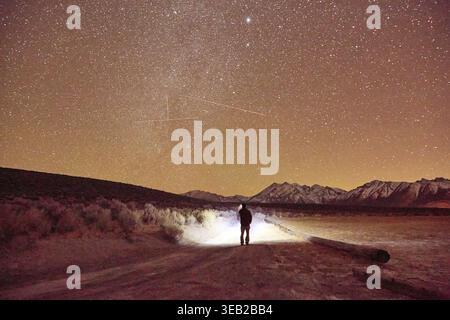 Persona che esplora il cielo notturno con torcia e montagne Foto Stock