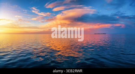 Ampio panorama di un tramonto tropicale sull'oceano calmo con colori arancio, rosso e viola come sfondo di texture Foto Stock