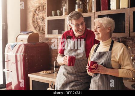 Coppie anziane che si godono un caffè insieme in un accogliente ambiente cucina nel pomeriggio Foto Stock