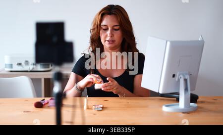 Giovane donna che crea video tutorial di bellezza online per gli abbonati ai social media Foto Stock