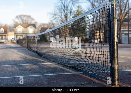 Vista ravvicinata della rete da tennis sul campo all'aperto nel quartiere residenziale, concetto di sport e tempo libero con bassa profondità di campo Foto Stock