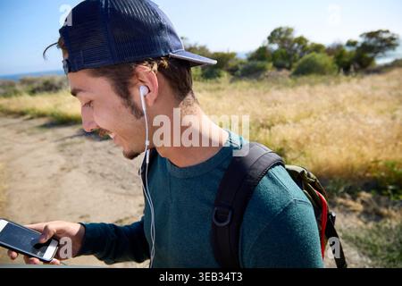 Giovane che ama la musica mentre fa escursioni all'aperto Foto Stock