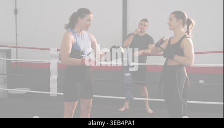 Guanti da boxe intercambiabili, due apprendisti che fissano gli avvolgimenti nell'anello da boxe con gesti da allenatore Foto Stock