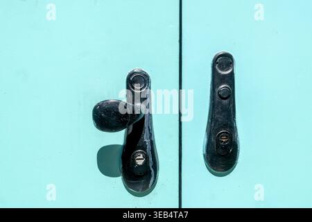 Primo piano delle maniglie delle portiere vintage in metallo nero su una superficie in metallo turchese Foto Stock