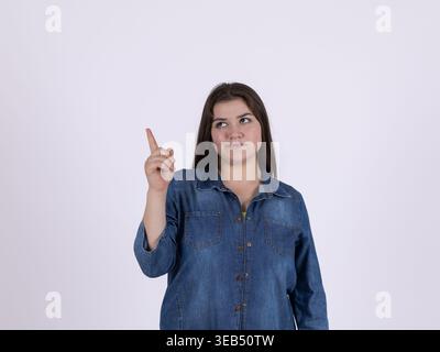 Giovane donna che guarda con attenzione e punta Foto Stock