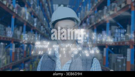 Uomo anziano in piedi nella corsia del magazzino, con elmetto bianco, giubbotto da lavoro, rivestimento digitale in HUD Foto Stock