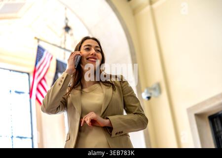 Donna che parla sullo smartphone in un ambiente di lavoro Foto Stock