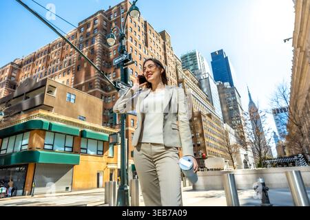 Donna d'affari che cammina a manhattan e parla su smartphone Foto Stock