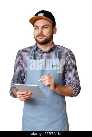 Maschio isolato in grembiule e cappuccio che reggono un tablet computer. Cameriere che prende l'ordine utilizzando un tablet digitale. Foto Stock