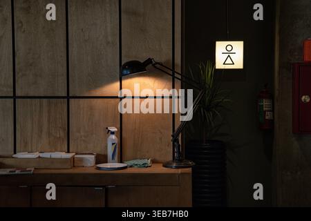 Batumi, georgia, 21 aprile 2026: Ristorante moderno o interni per uffici con lampada da scrivania nera, cartello per servizi igienici unisex ed estintore. Caldo Foto Stock